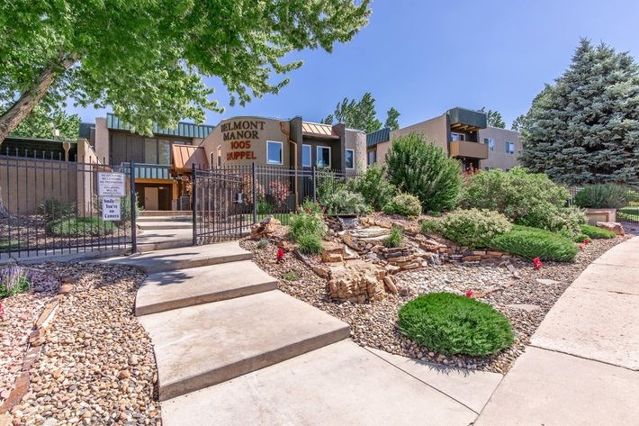 The image shows a gated entrance to a building named Elmont Hampton Manor Apartments.