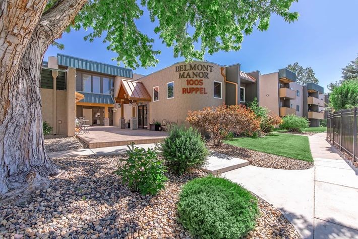 A large tree is in front of a building with a sign that says "Delmont Manor".