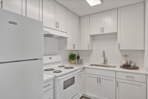 a kitchen with white cabinets and white appliances and a sink