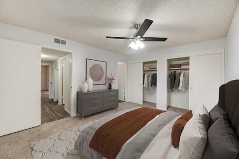 A bedroom with a bed, dresser, and a ceiling fan.