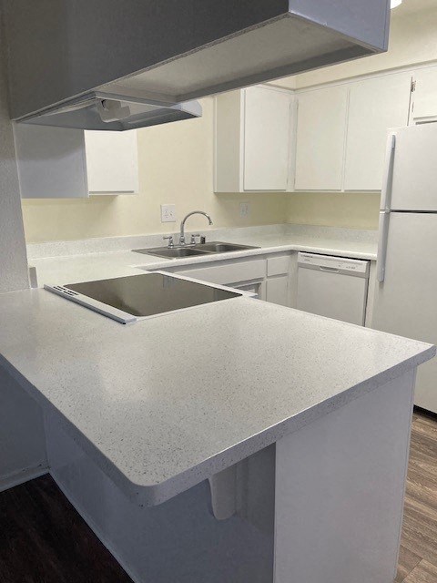 A white kitchen with a sink and a refrigerator.