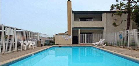a swimming pool in front of a building with a fence