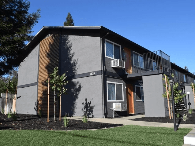 the exterior of a building with a yard and a balcony