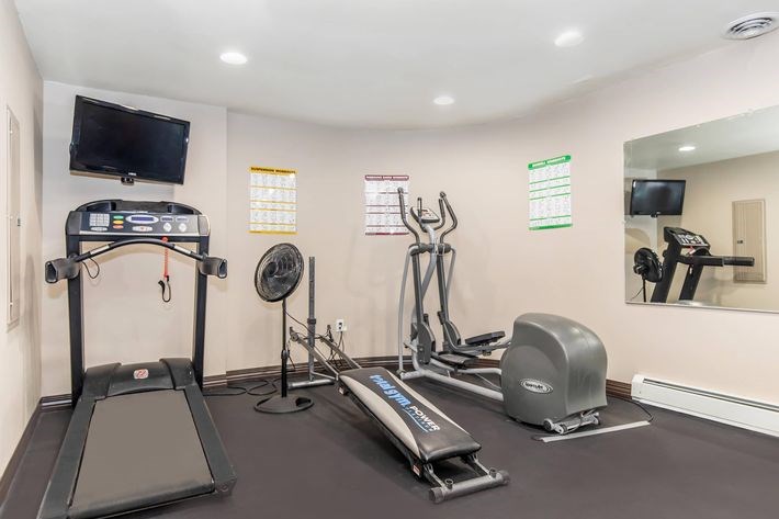 A home gym with a treadmill, exercise bike, and other equipment.