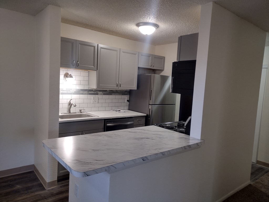 A kitchen with a marble countertop and stainless steel appliances.