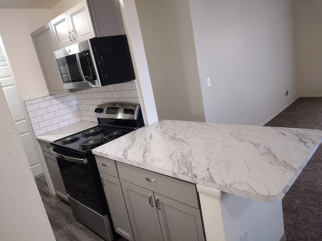 A kitchen with a marble countertop and stainless steel appliances.