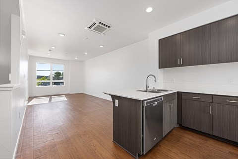 A kitchen with dark wood floors and white walls.