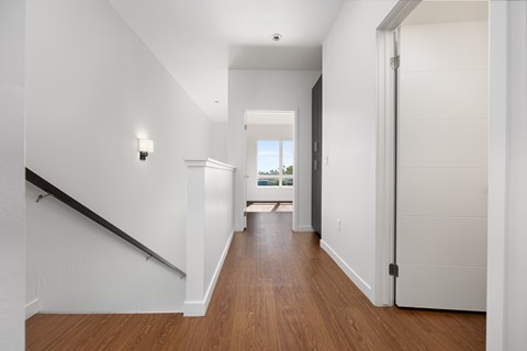 A long hallway with a wooden floor and white walls.