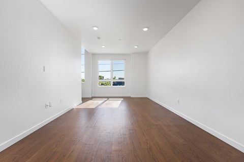A room with wooden floors and a window overlooking a green landscape.