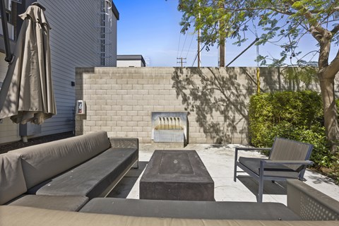 A patio with a couch, table, and umbrella.