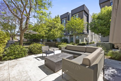 A modern outdoor seating area with a concrete table and couches.