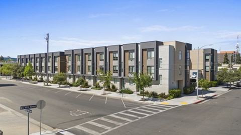 A street view of apartment buildings with a clear blue sky above.