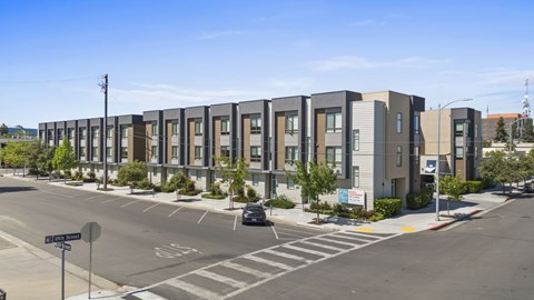 A street view of apartment buildings with a car parked on the side of the road.