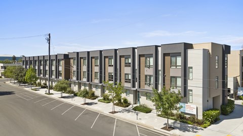 A row of modern townhouses with a clear blue sky above.