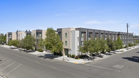 A street view of a row of modern townhouses with a clear blue sky above.