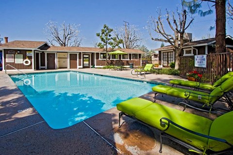 a swimming pool with green chairs around it