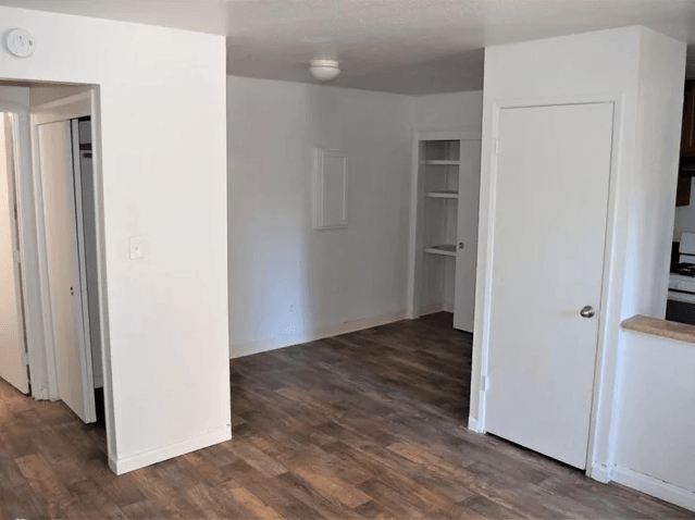 an empty living room with white walls and a wood floor