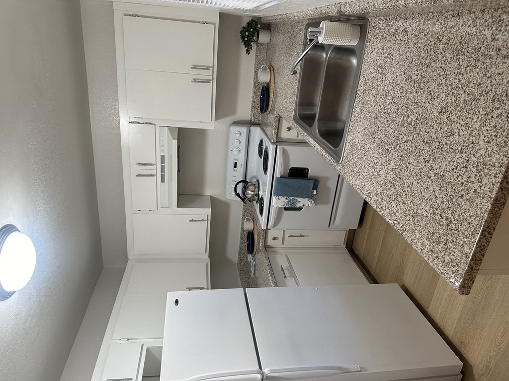 a small kitchen with a white counter top and a sink