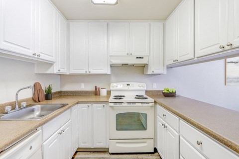 a kitchen with white cabinets and a sink and a stove