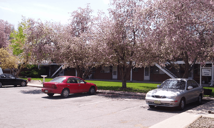 a red car parked in a parking lot in front of a brick building