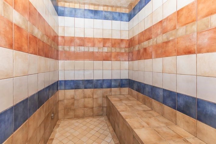 A bathroom with a blue and orange tiled shower.