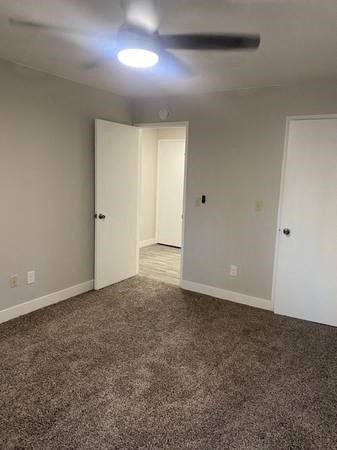 an empty room with a ceiling fan and a door