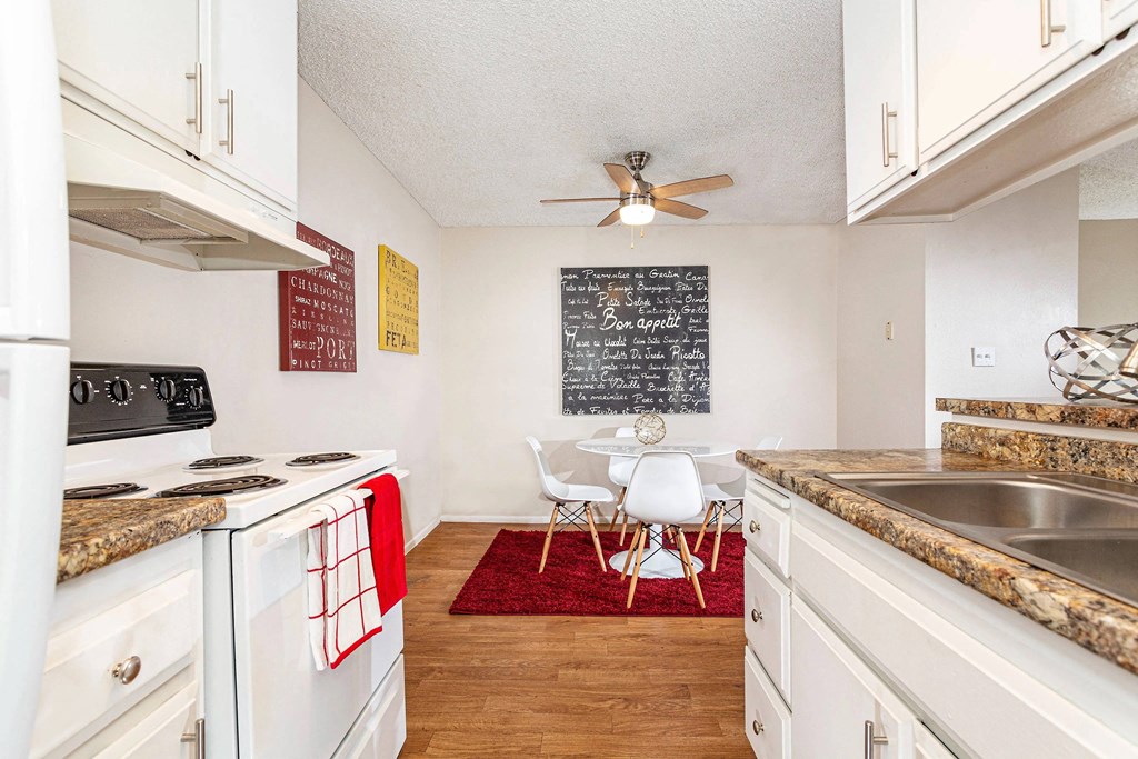 a kitchen with white cabinets and appliances and a dining room with a table and chairs