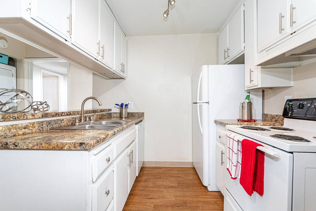 a kitchen with white appliances and granite counter tops and white cabinets