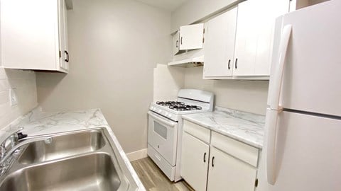 a kitchen with white cabinets and appliances and a stainless steel sink