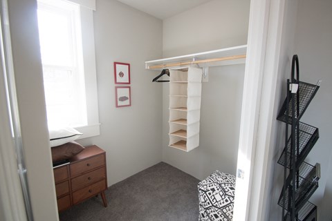 a walk in closet in a bedroom with a dresser and a window