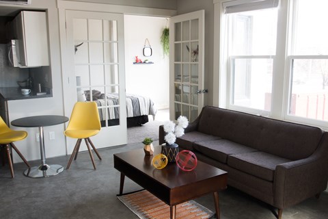a living room with a grey couch and yellow chairs