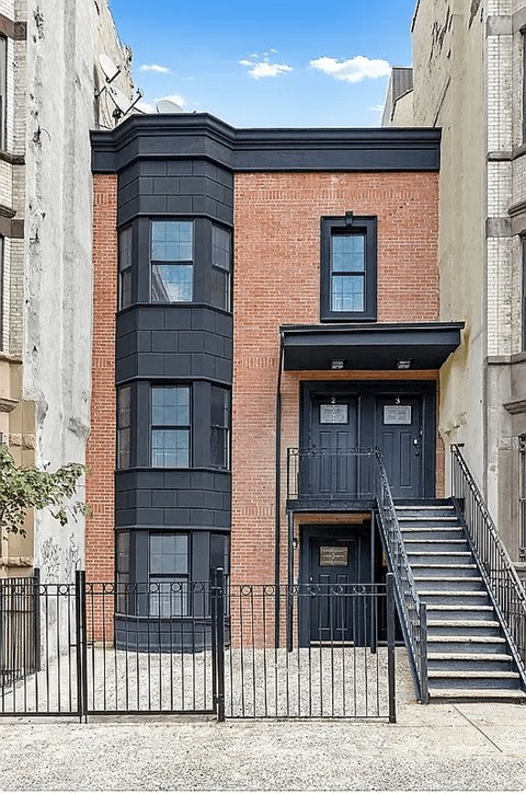A black and red building with a black door and stairs leading to it.