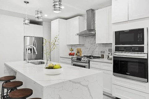 A modern kitchen with a marble countertop and stainless steel appliances.