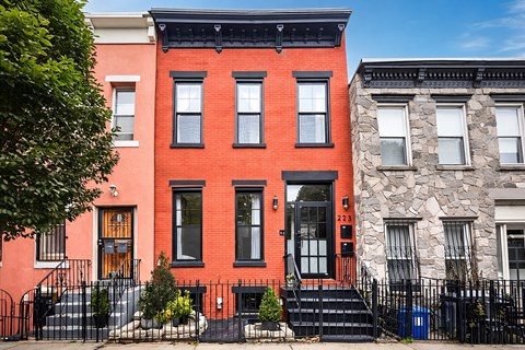 A red brick house with a black iron fence in front.
