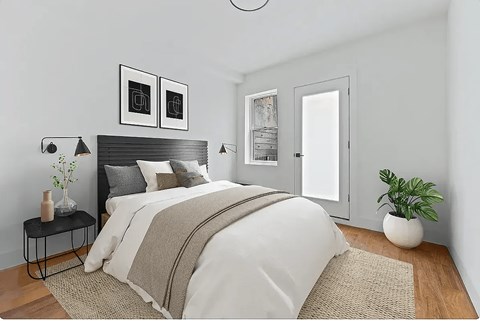 A bedroom with a large bed and a plant on the side table.