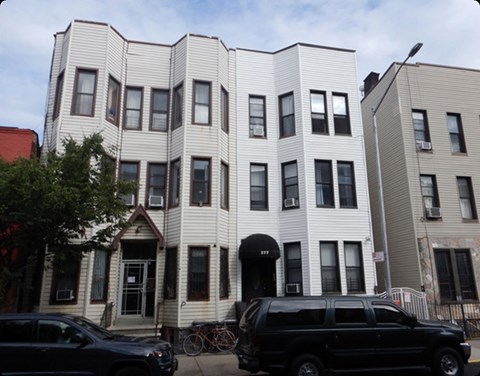 A black SUV is parked in front of a white building.