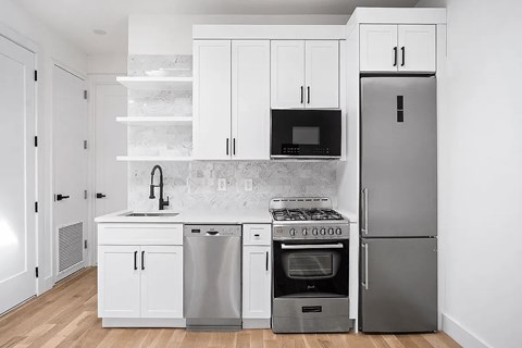 A modern kitchen with white cabinets and stainless steel appliances.