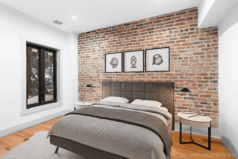 A bedroom with a brick wall and a bed.
