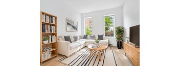 A living room with a white couch, a coffee table, a bookshelf, and a television.