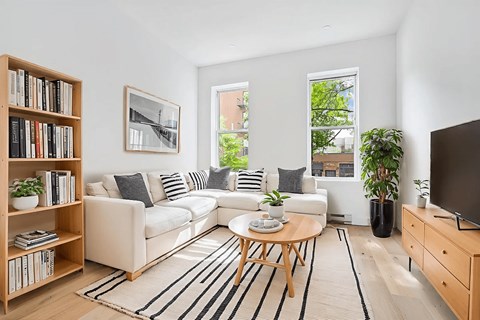 A living room with a white couch, a coffee table, a bookshelf, and a television.