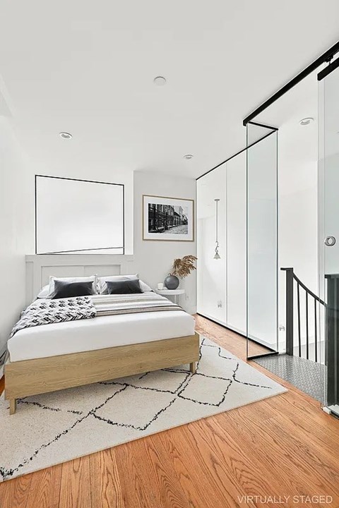 A bedroom with a bed, a rug, and a painting on the wall.