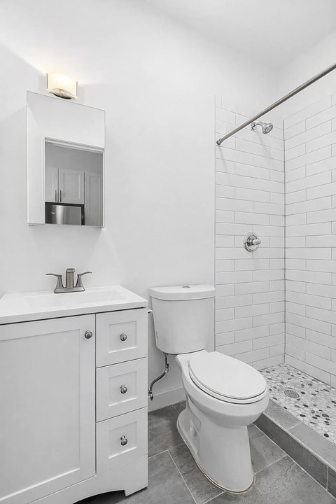A white bathroom with a toilet, sink, and shower.