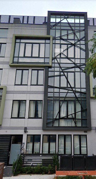 A modern building with a large window and a black metal structure on the side.
