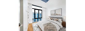 A bedroom with a large bed and a view of a city skyline.