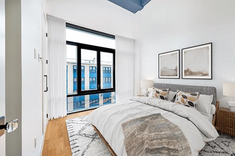 A bedroom with a large bed and a view of a city skyline.