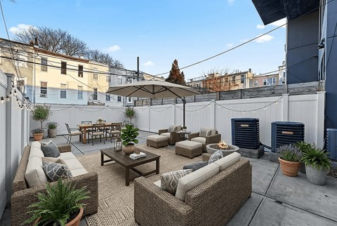 A patio with a wicker sofa, chairs, and a table with a plant on it.