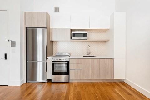 A kitchen with a stainless steel refrigerator, oven, and microwave.