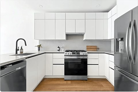 A modern kitchen with white cabinets and stainless steel appliances.