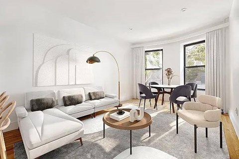A living room with a white sofa, a wooden table, and a lamp.