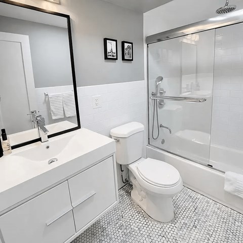 A white toilet sits in a bathroom next to a sink and a shower.